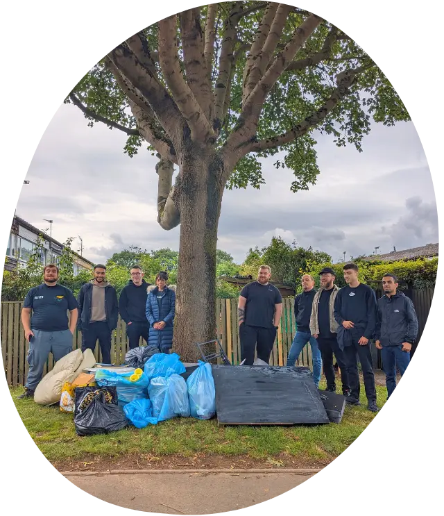 9 volunteers standing under a tree with many bags of rubbish that they worked hard to collect